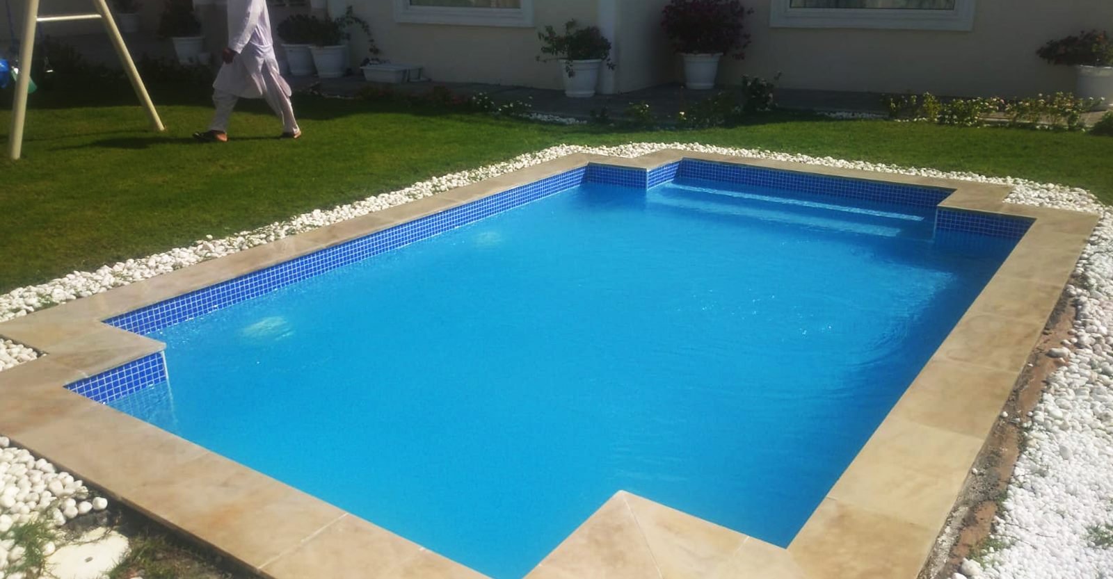 Blue-tiled rectangular swimming pool beside a villa